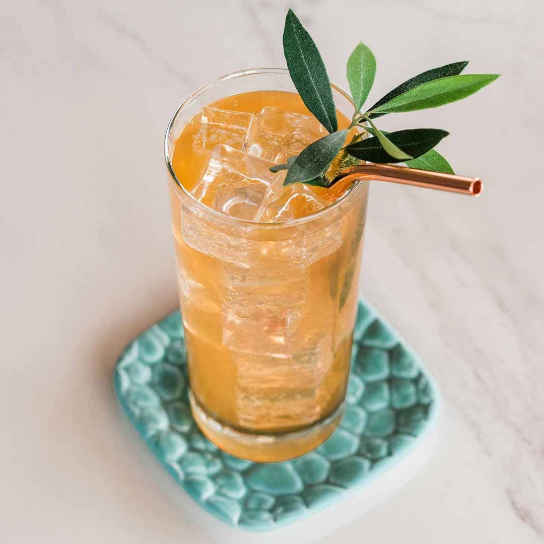 Gin and tonic made with Jo's Original tonic syrup, over ice in a tall glass with a copper straw