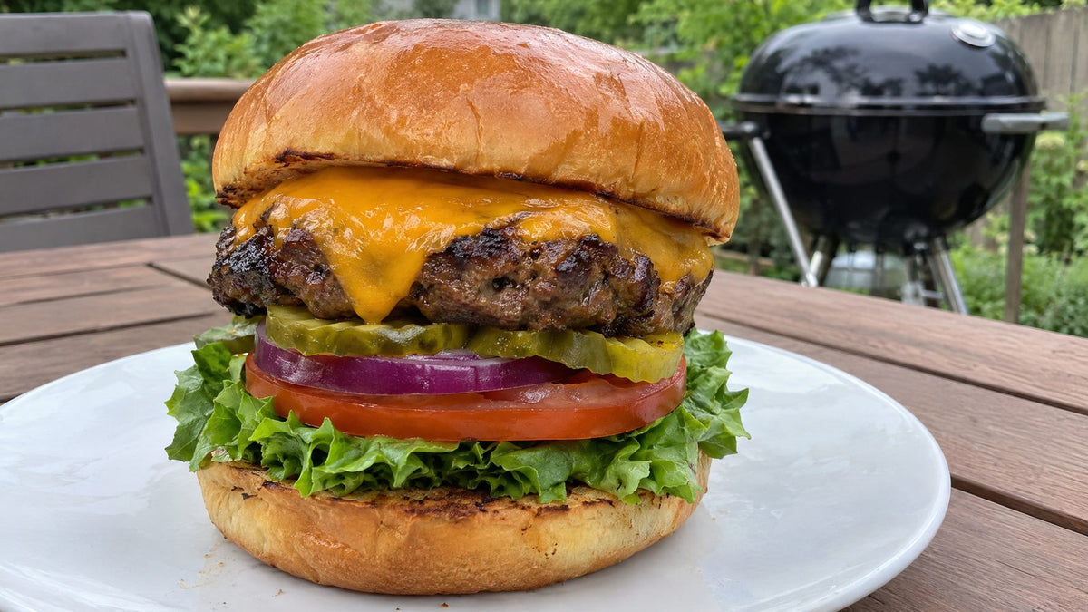 Grilled cheeseburger made with homemade burger seasoning on a backyard patio table