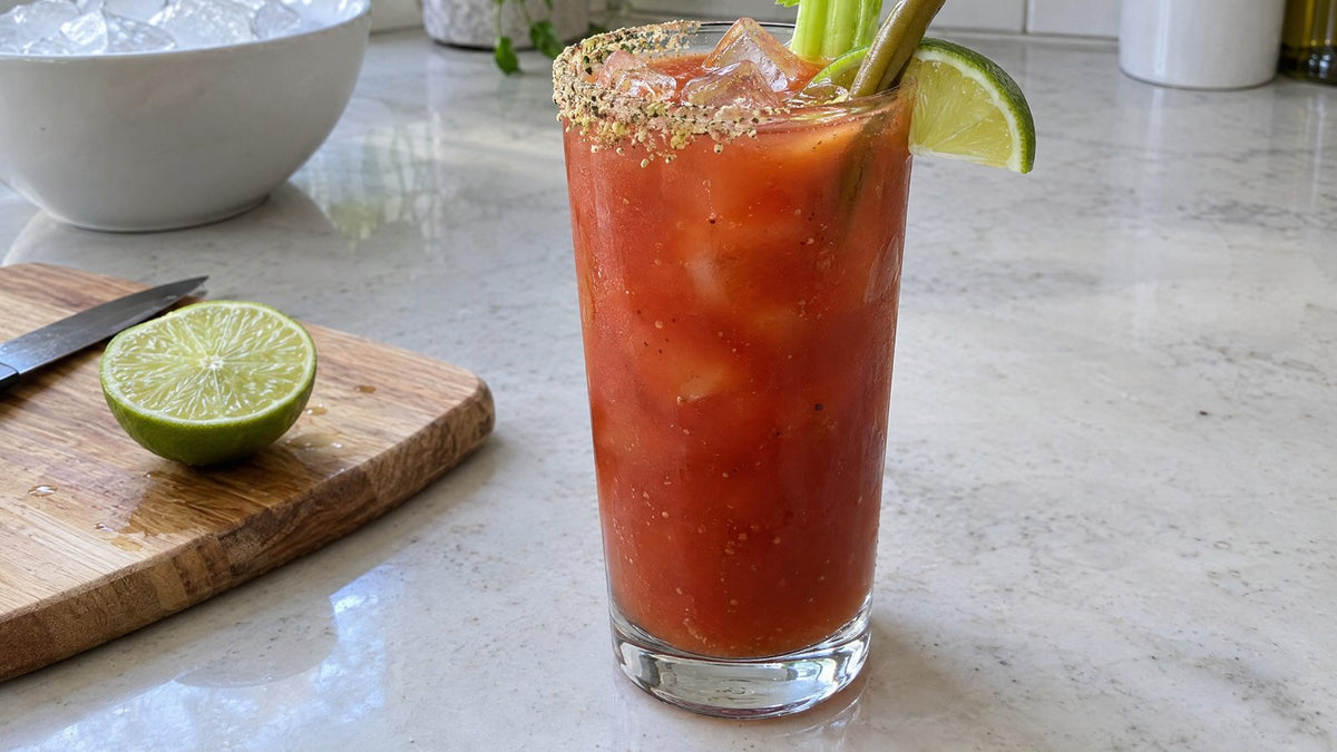 Bloody Caesar made with Clamato juice, with a celery salt rim, celery stalk, and lime wedge