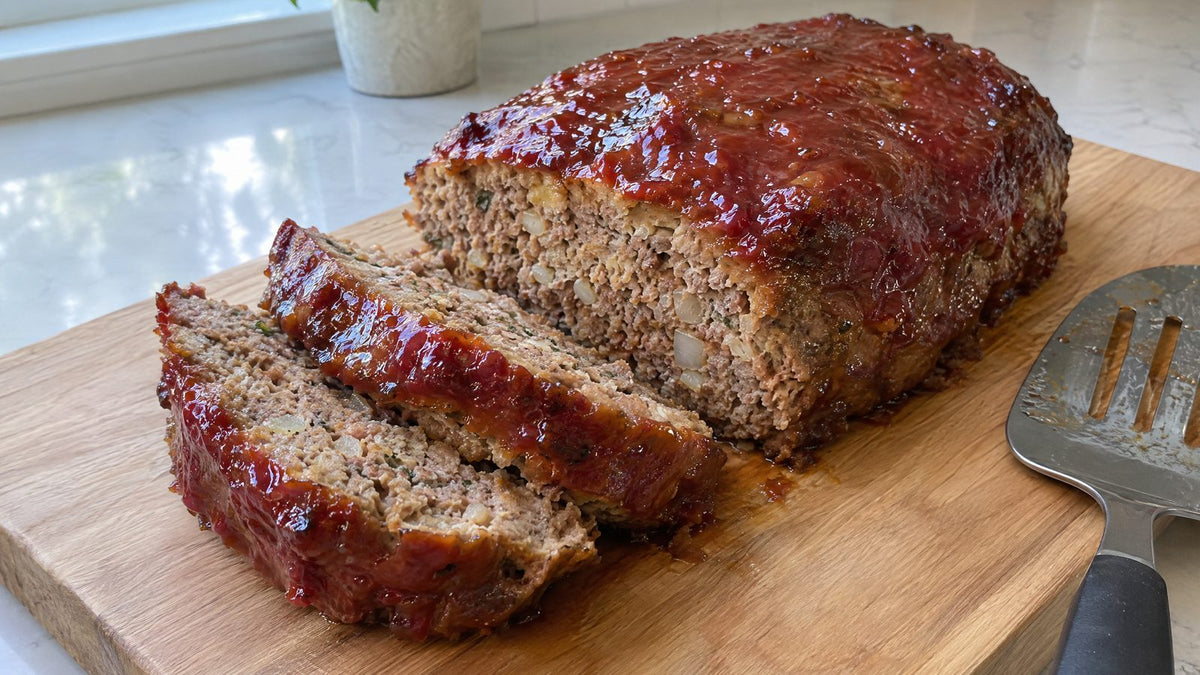 Glazed meatloaf made with homemade meatloaf seasoning, sliced on a cutting board