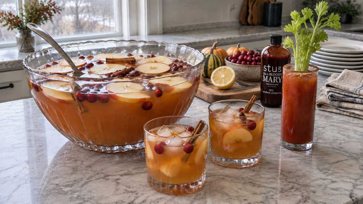 Thanksgiving cocktails: apple cider bourbon punch with cranberries and cinnamon sticks, and a Bloody Mary next to a bottle of Stu's