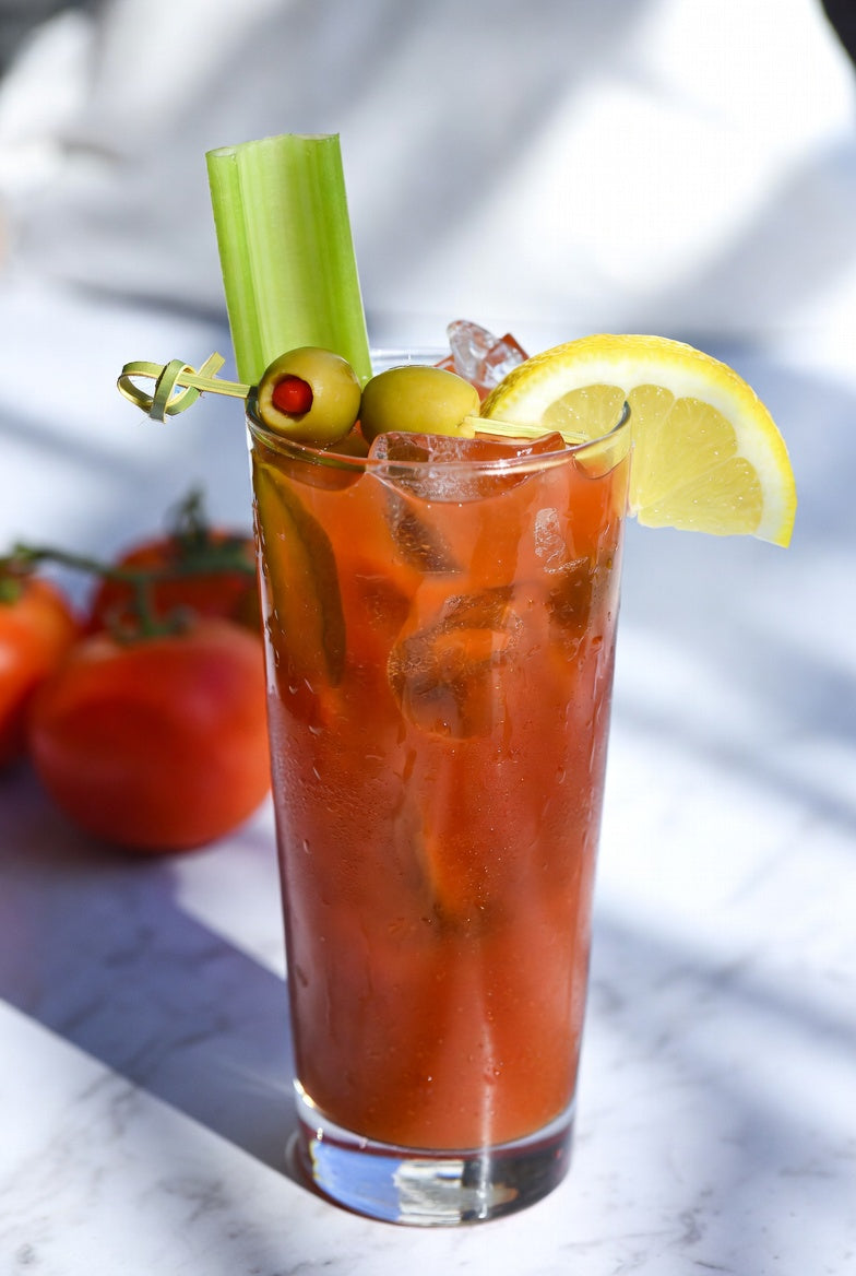 Non-alcoholic Virgin Mary in a tall glass garnished with a celery stalk, green olives, and a lemon wedge