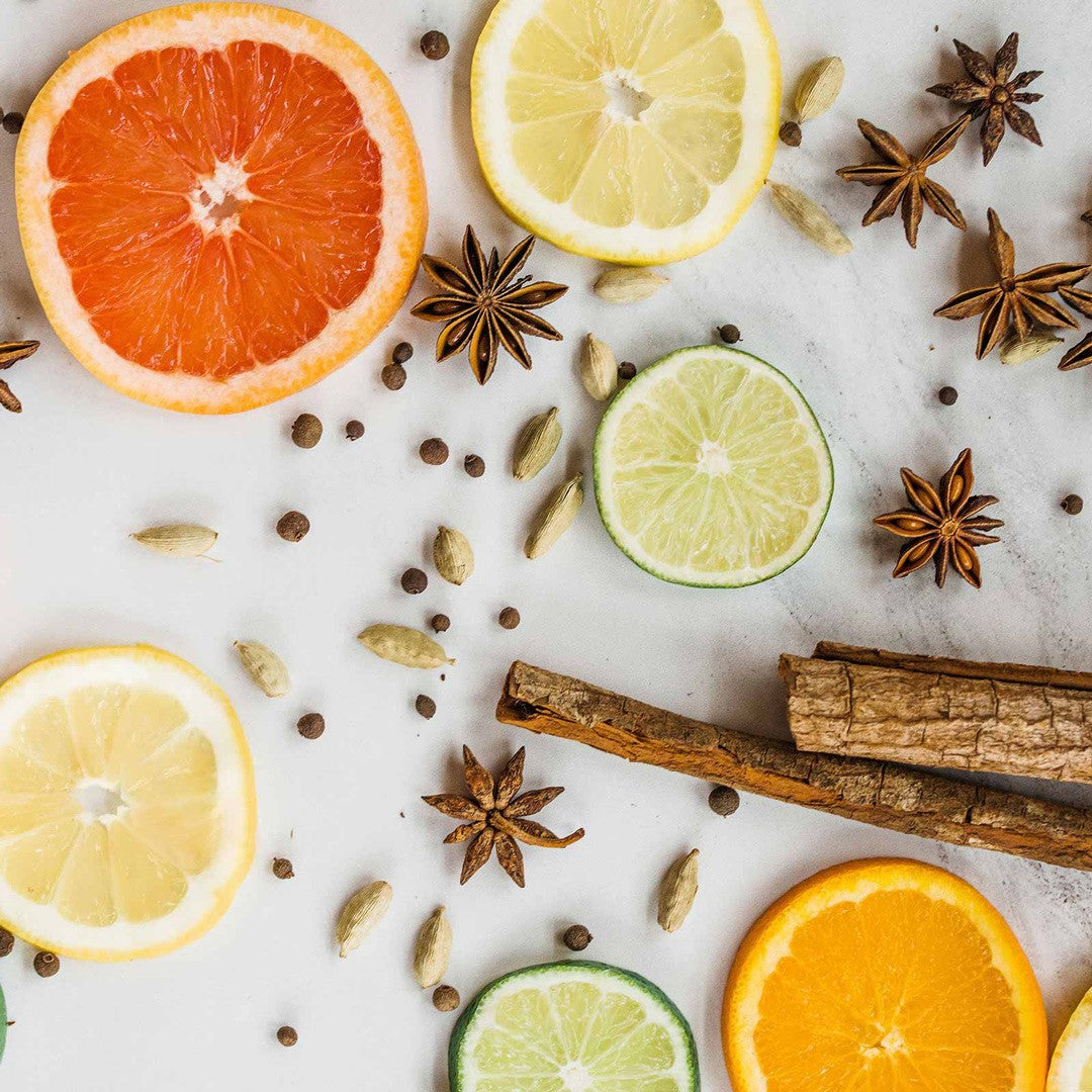 Fresh grapefruit, orange, lemon and lime slices with whole spices and bark on white marble